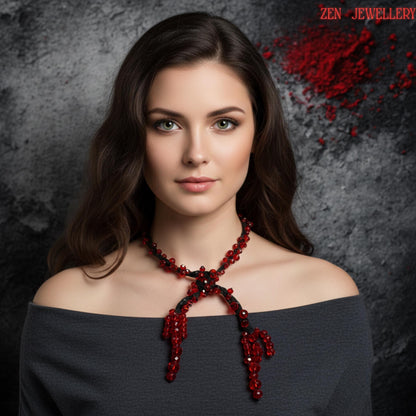 Elegant handmade boho necklace featuring vivid ruby red crystals arranged asymmetrically along soft black crochet cords. The faceted stones create brilliant reflections while the dark woven structure adds texture and depth to the design. The necklace has a fluid artistic silhouette with crystals positioned in clusters and scattered patterns for a couture-inspired appearance. The handcrafted structure feels expressive, feminine, lightweight, and c
