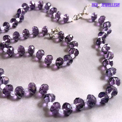 Handmade purple crystal jewellery set photographed with lilac flowers featuring sparkling faceted beads white pearl spacers silver chain closures and elegant matching bracelet and necklace arrangement for bridal fashion styling.