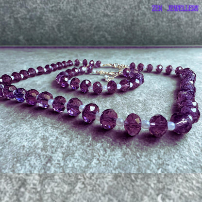 Coordinated crystal necklace and bracelet set featuring deep lavender purple faceted beads separated by glossy white pearl style spacer beads with adjustable silver extension chains and elegant handcrafted styling.