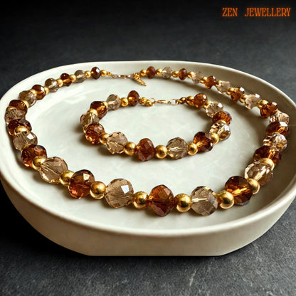 Sparkling crystal necklace featuring faceted caramel and champagne crystal beads arranged with polished gold spacer beads, creating elegant symmetry and luxurious handcrafted texture. The matching bracelet mirrors the necklace design perfectly for a complete coordinated jewellery set.