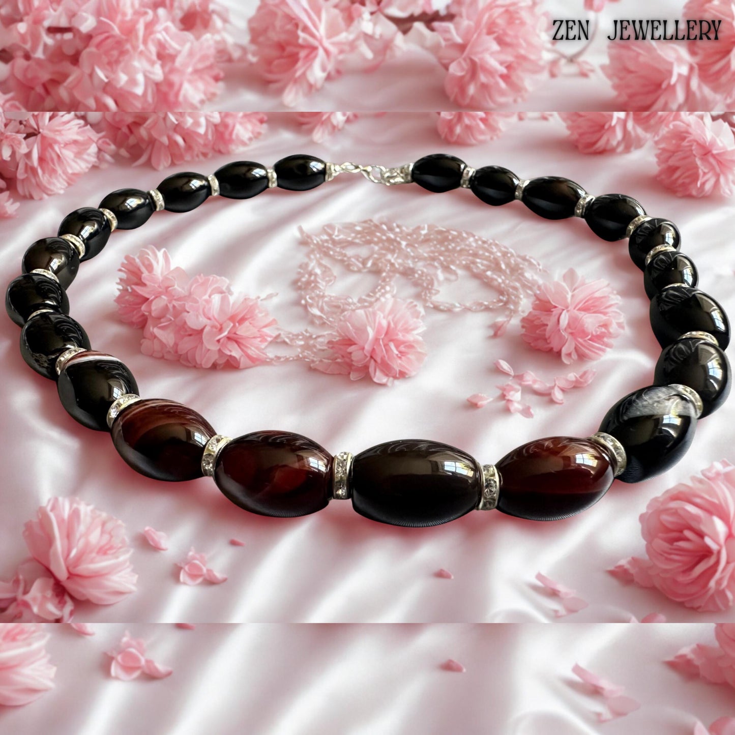 Handmade black agate statement necklace featuring polished gemstone beads with deep burgundy striped accents and rhinestone spacer details. The glossy reflective stones create luxurious shine while the silver clasp and extension chain provide adjustable comfort. Soft floral styling in the background highlights the elegant feminine aesthetic. Necklace length is 47 cm approximately 18.5 inches for stylish everyday or evening wear.