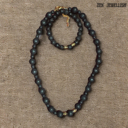 Handmade black lava stone jewellery set with textured volcanic beads, golden artisan spacers, and a warm earthy minimalist aesthetic. The necklace and bracelet feature carefully balanced bead sizes and elegant gold-tone closures that create a timeless handcrafted appearance inspired by natural volcanic materials and modern bohemian fashion.