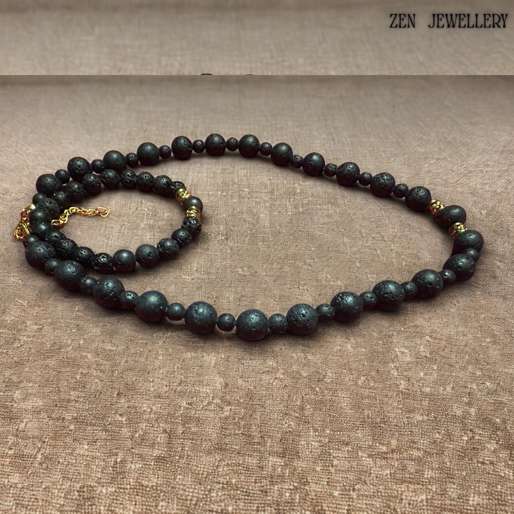 Matching lava stone bracelet shown with matte black volcanic beads and decorative gold spacer accents. The porous natural lava stones create an earthy bohemian aesthetic, while the polished golden details add elegance and sophistication. The bracelet fits comfortably on a beige background and pairs beautifully with the coordinating necklace for a timeless handcrafted jewellery set.