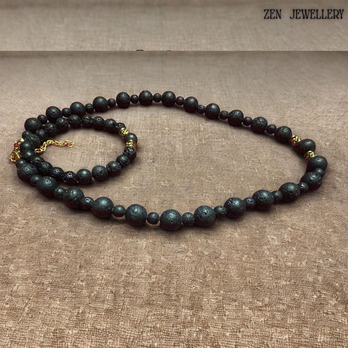 Matching lava stone bracelet shown with matte black volcanic beads and decorative gold spacer accents. The porous natural lava stones create an earthy bohemian aesthetic, while the polished golden details add elegance and sophistication. The bracelet fits comfortably on a beige background and pairs beautifully with the coordinating necklace for a timeless handcrafted jewellery set.