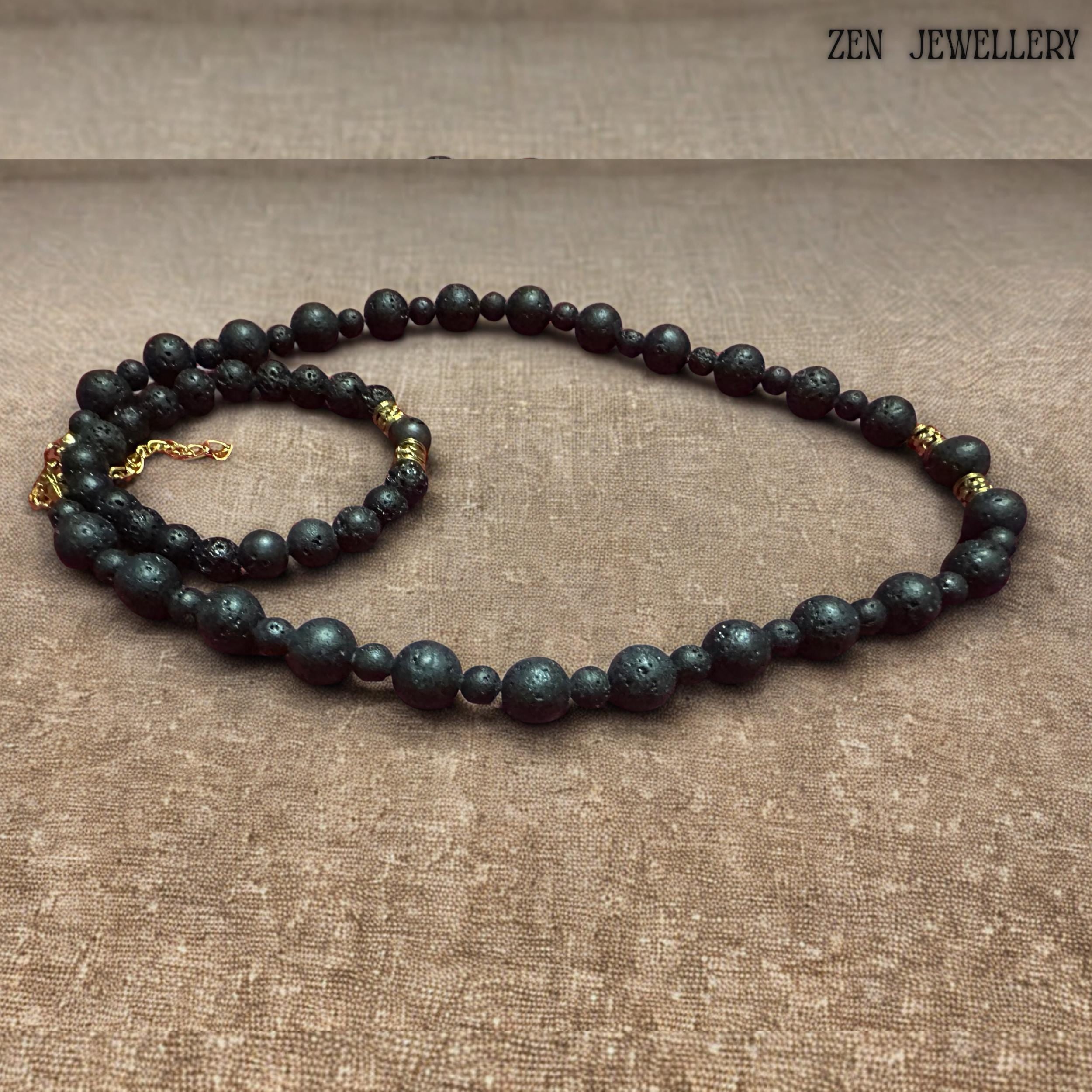 Matching lava stone bracelet shown with matte black volcanic beads and decorative gold spacer accents. The porous natural lava stones create an earthy bohemian aesthetic, while the polished golden details add elegance and sophistication. The bracelet fits comfortably on a beige background and pairs beautifully with the coordinating necklace for a timeless handcrafted jewellery set.