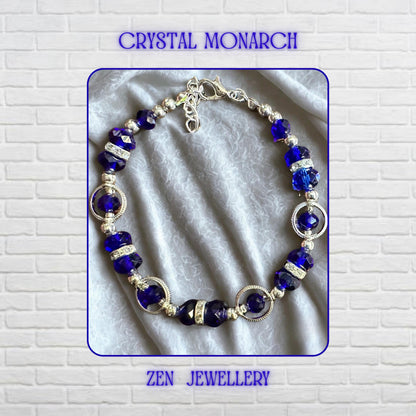 Close-up view highlighting the rich sapphire blue crystal beads positioned between bright silver-tone accents and shimmering rhinestone spacers. The faceted surfaces create brilliant reflections from multiple angles, enhancing the bracelet’s glamorous appearance. The carefully balanced arrangement of bead sizes creates visual harmony and elegant flow. Decorative silver ring elements frame selected crystal sections, while the adjustable fastening