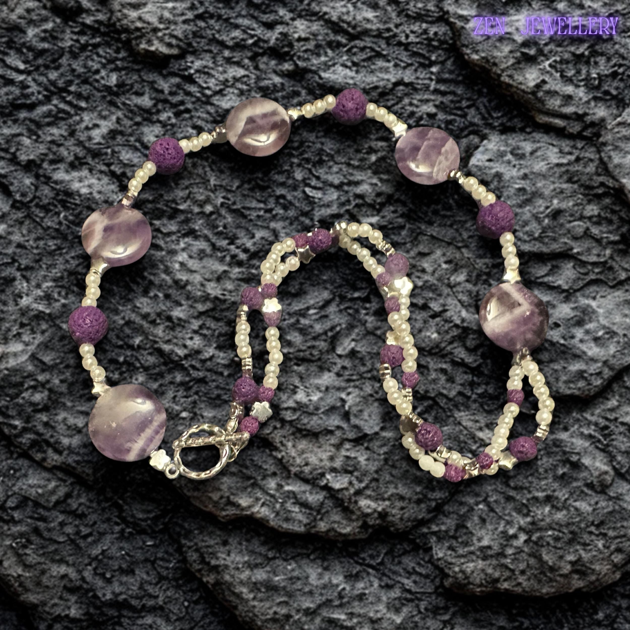 The flowing layered design of this amethyst pearl necklace creates elegant texture and artistic movement. The rich purple tones contrast beautifully against the delicate white beads while silver spacer details add sparkle and balance to the handmade jewellery piece.