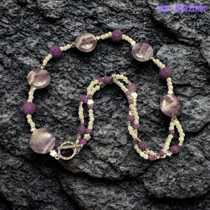 The flowing layered design of this amethyst pearl necklace creates elegant texture and artistic movement. The rich purple tones contrast beautifully against the delicate white beads while silver spacer details add sparkle and balance to the handmade jewellery piece.