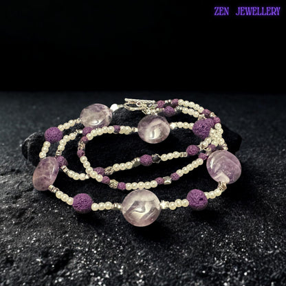 This amethyst-inspired necklace combines polished lavender beads, textured lava stones, silver accents, and delicate pearl-style spacers in a balanced handmade design. The artistic arrangement creates a lightweight statement necklace full of texture and feminine charm.