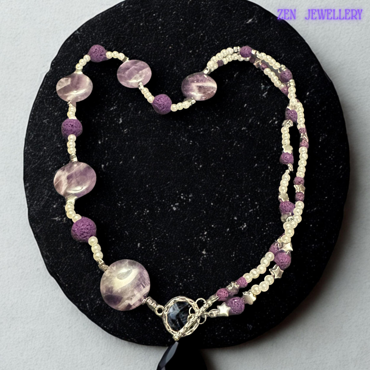 Small white pearl-style beads separate the faceted purple crystal beads and create a soft elegant contrast throughout the necklace. The layered beadwork creates a graceful flowing appearance inspired by modern bohemian and spiritual jewellery trends.