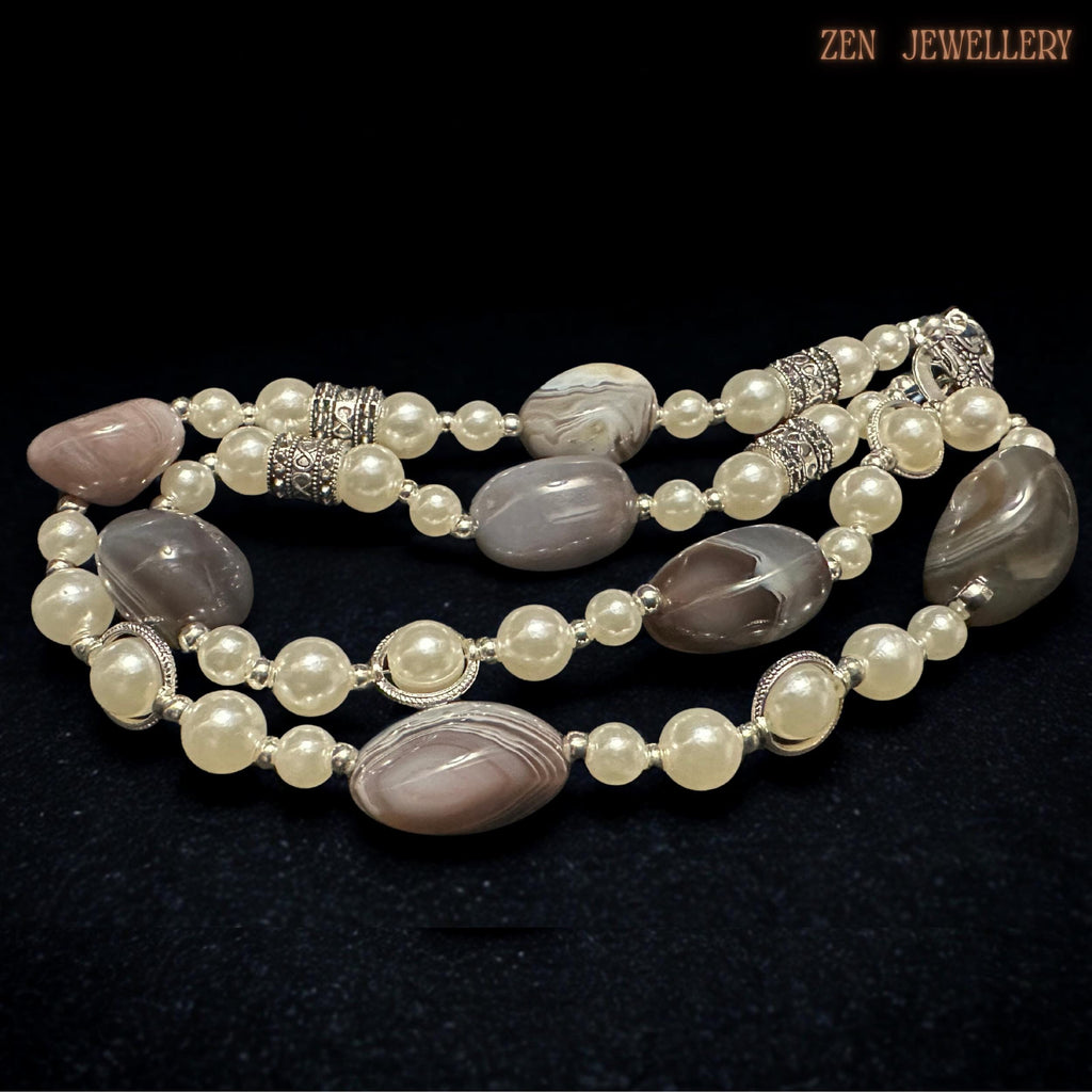 Handmade BOTSWANA AGATE necklace photographed from above to showcase the natural striped grey agate stones paired beautifully with smooth ivory pearl beads and silver decorative spacers. The elegant arrangement creates soft contrast between earthy gemstones and classic pearls while the silver toggle clasp adds timeless vintage detail.