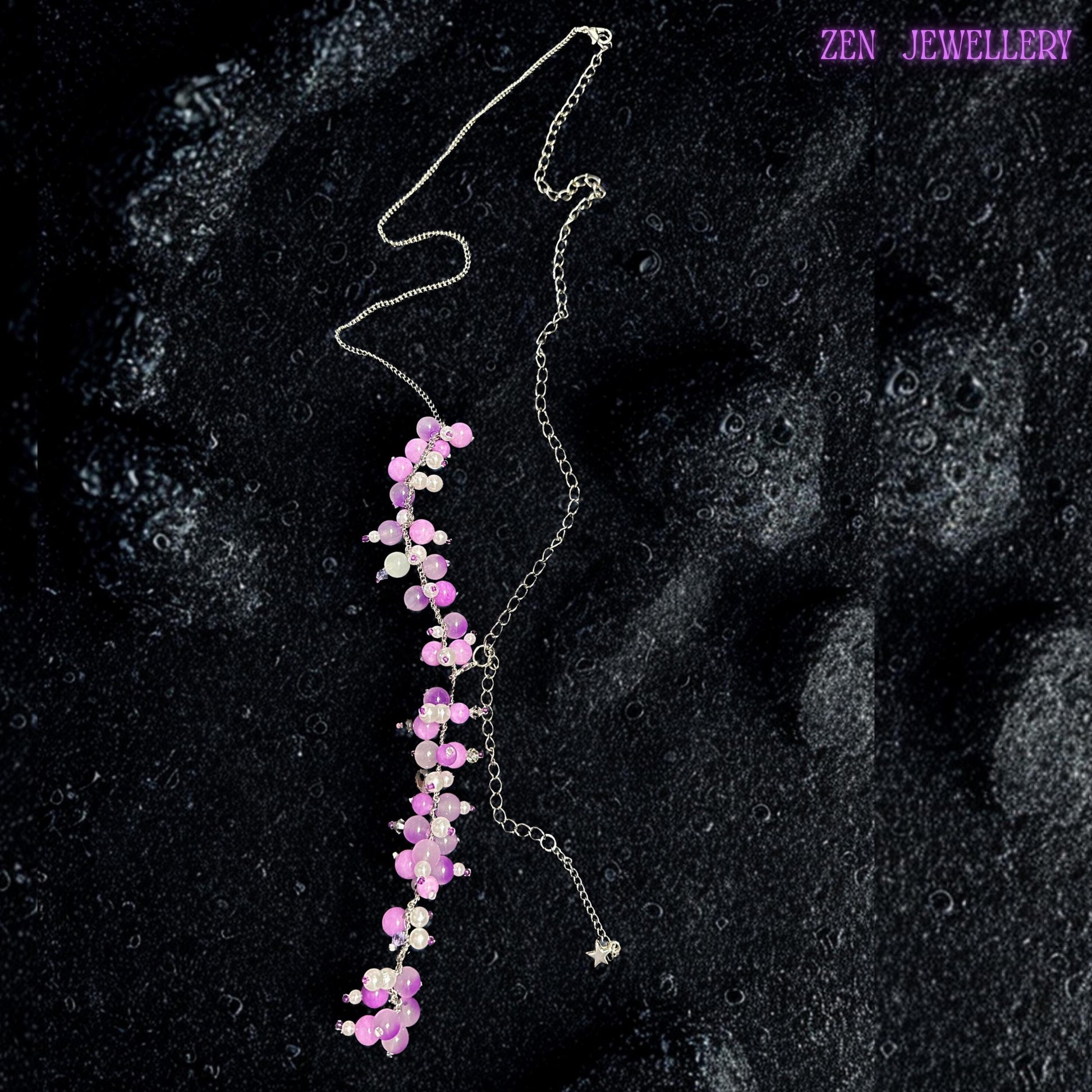 Elegant boho necklace displayed flat on a dark stone surface, highlighting delicate pink and lavender gemstone clusters attached to silver chain strands. The handcrafted arrangement creates soft layered movement with pearl white beads and polished pastel crystals placed throughout the design. Small silver spacer beads and reflective accents add sparkle without overpowering the feminine look. This necklace is ideal for weddings, bridal events, fes