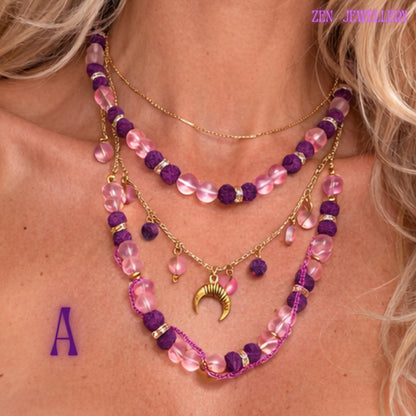 • Detailed product image focusing on the celestial crescent moon pendant attached to a delicate gold chain surrounded by small floating blush pink gemstone charms. The polished gold crescent contrasts beautifully with the soft pink and purple tones while adding mystical symbolism and feminine energy to the handcrafted layered gemstone jewellery set inspired by celestial and spiritual fashion.