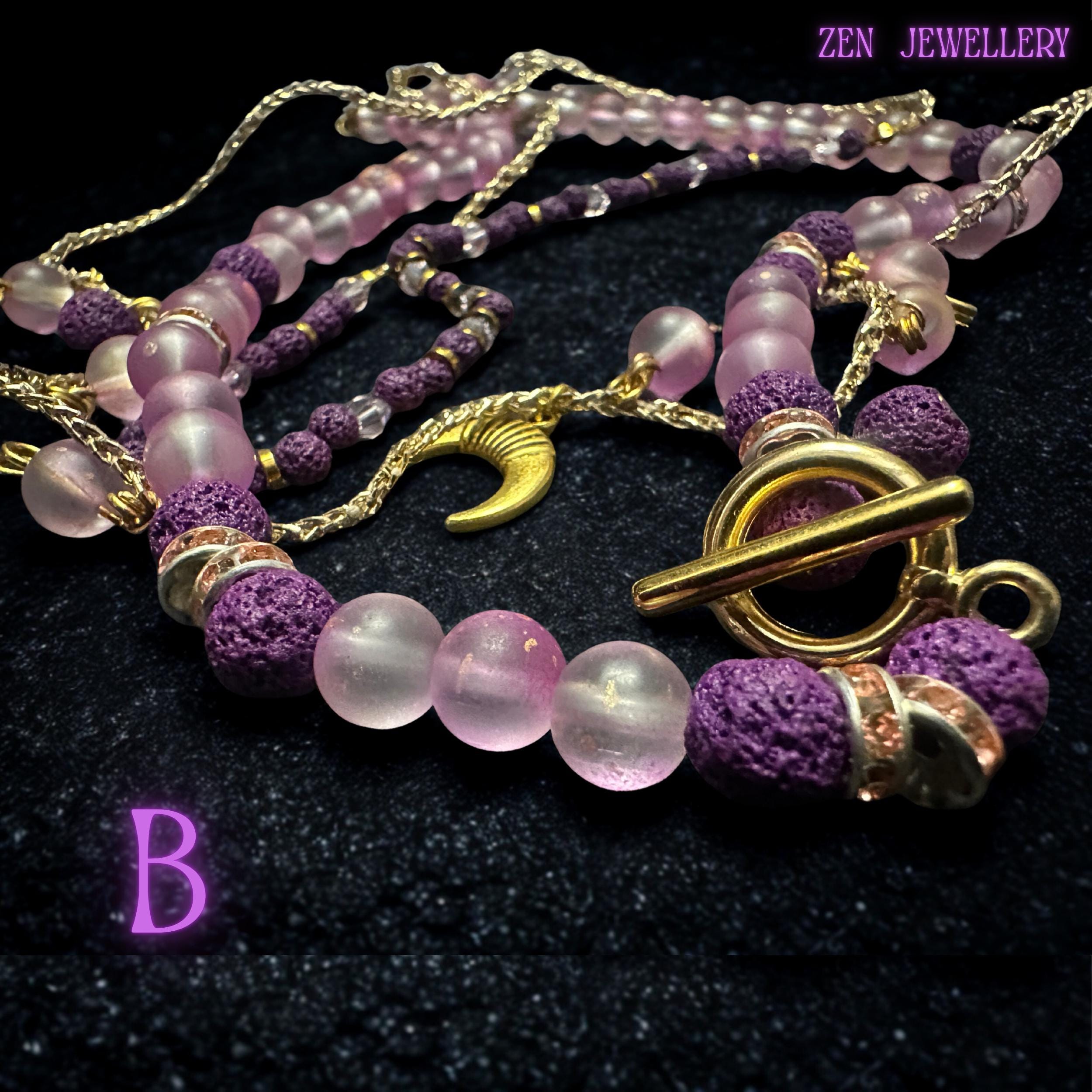 • Elegant flat-lay photograph showing the layered necklace carefully arranged to reveal the graceful drape and flowing movement of the fine gold chain strands. Small dangling gemstone charms attached to the chain create playful detail while the crescent moon pendant anchors the celestial design beautifully. The soft pink and purple palette gives the jewellery set a dreamy romantic appearance.