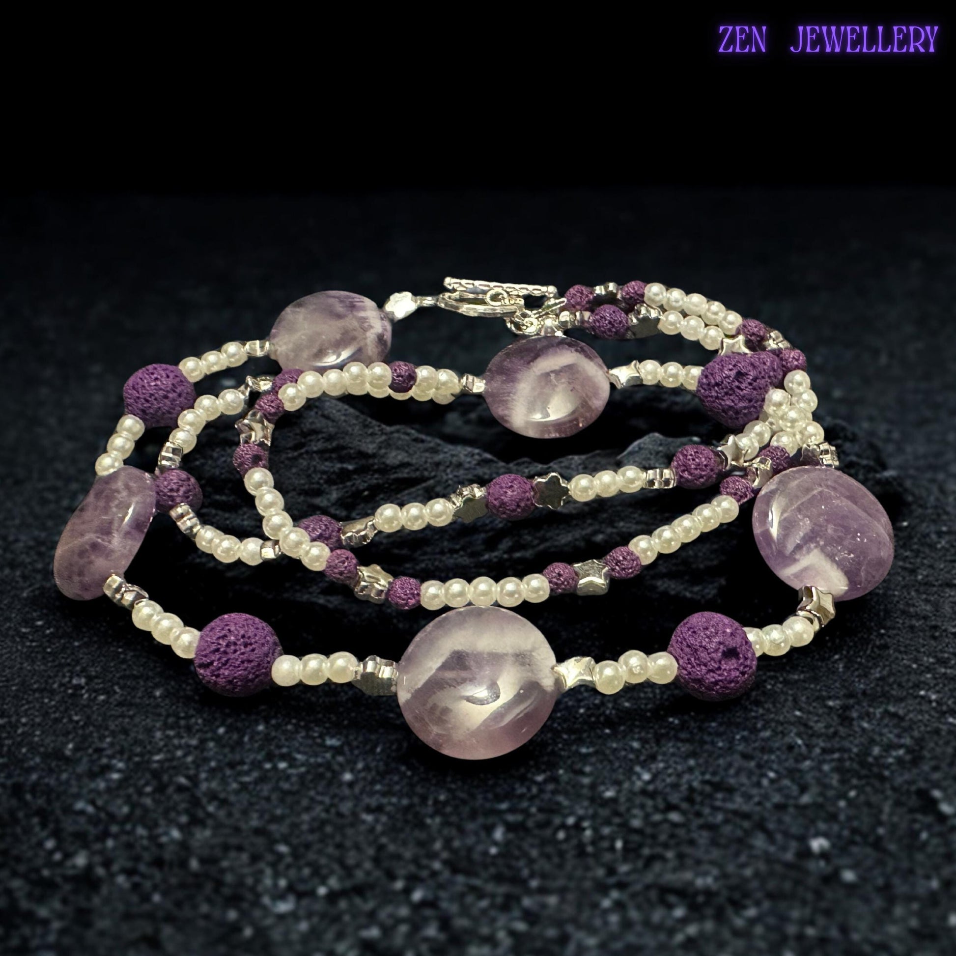 The silver toggle clasp and dangling bead details give this handmade purple necklace a unique artisan finish. The textured lava stone beads add depth and contrast while the glossy crystal-style beads create soft sparkle and luxurious movement.