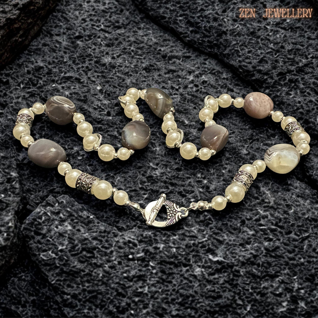 Elegant artisan gemstone necklace featuring polished BOTSWANA AGATE beads arranged with creamy pearls and detailed silver decorative elements for a luxurious bohemian appearance. The natural striped agate stones create organic texture while the pearls soften the design with feminine elegance. Silver rhinestone spacers add subtle sparkle and refined detail throughout the handcrafted composition.