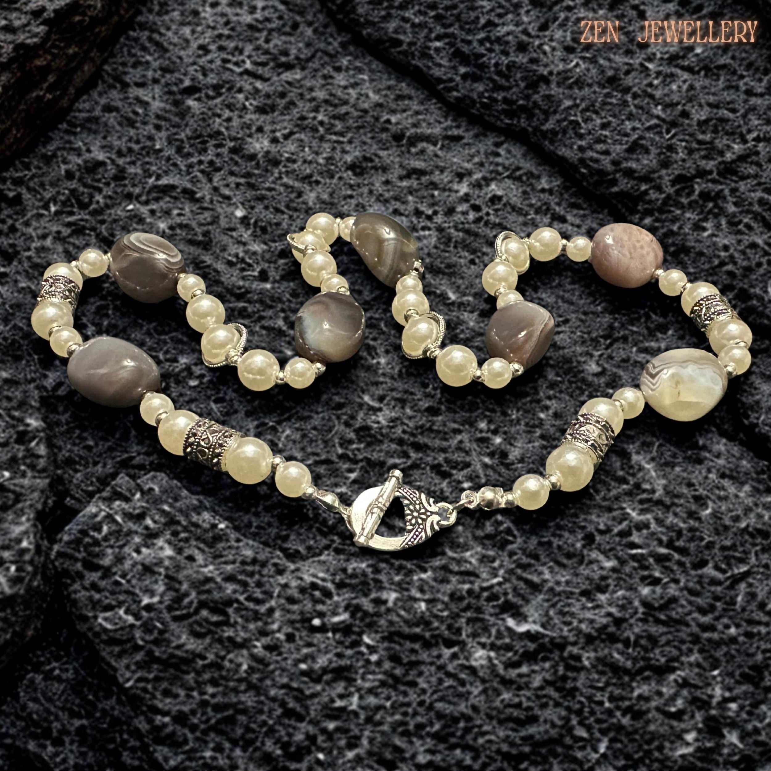 Elegant artisan gemstone necklace featuring polished BOTSWANA AGATE beads arranged with creamy pearls and detailed silver decorative elements for a luxurious bohemian appearance. The natural striped agate stones create organic texture while the pearls soften the design with feminine elegance. Silver rhinestone spacers add subtle sparkle and refined detail throughout the handcrafted composition.