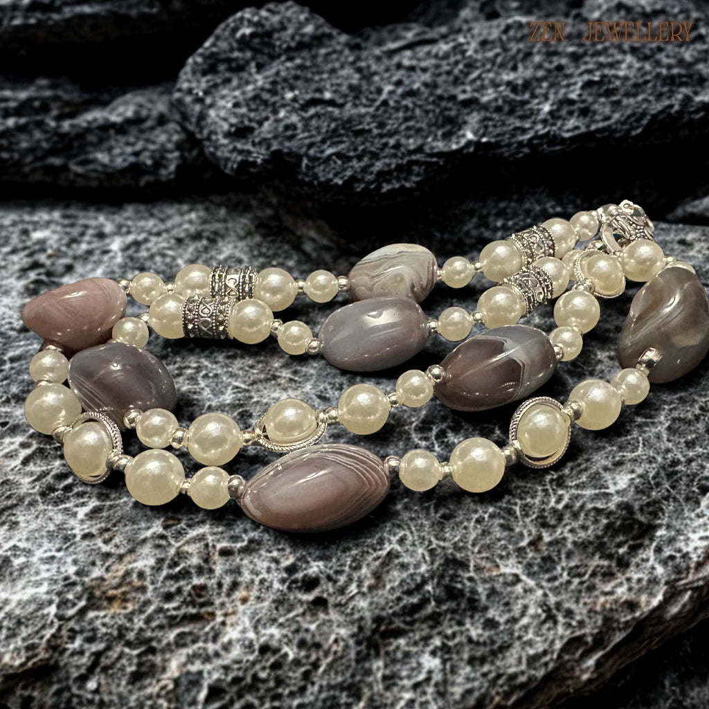 Detailed photograph of the BOTSWANA AGATE necklace highlighting the natural patterns inside the polished grey agate stones and the soft shine of the ivory pearl beads. Decorative silver spacers and toggle clasp create vintage-inspired texture while the layered handmade arrangement gives the necklace artistic elegance and balanced structure.