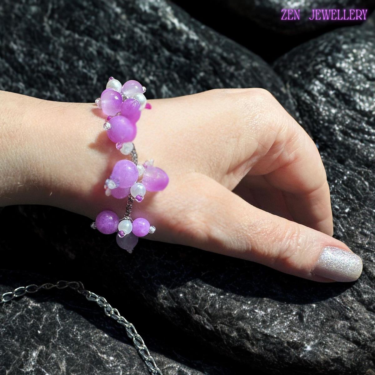 Handcrafted silver bracelet with cascading pastel gemstone bead clusters displayed with matching bracelet and earrings on a dark textured surface. The glossy beads feature soft pink, lavender, pearl white, and lilac tones arranged asymmetrically for a natural, artistic look. Tiny silver accents and reflective spacer beads create soft sparkle and luxurious detail throughout the jewellery set.