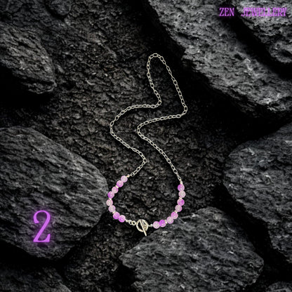 Feminine statement necklace featuring layered silver chain strands decorated with pastel pink, lavender, lilac, and purple gemstone beads attached to dangling chain details. The handcrafted arrangement creates soft movement and artistic texture while polished gemstone surfaces provide glossy shine. Chunky silver chain links contrast beautifully with the delicate pastel bead colours for a modern romantic look. The necklace is worn with a pale pink