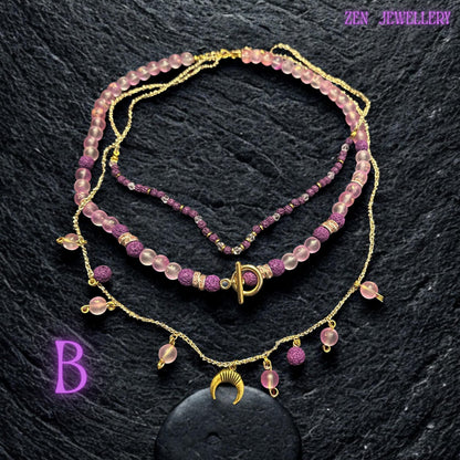 • Close-up detail of the pink gemstone beads revealing their semi-translucent frosted finish and smooth polished surface. The beads reflect soft warm light creating a gentle glowing effect against the dark textured background. Tiny pink seed beads woven into the lower strand add intricate handcrafted detail while gold accents bring elegance and refined sparkle to the romantic bohemian design.