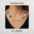 Elegant BOTSWANA AGATE gemstone necklace displayed on a textured dark background featuring polished grey striped agate stones combined with creamy ivory pearl beads and decorative silver rhinestone spacers. The handmade layered design creates a sophisticated bohemian appearance with soft neutral tones and artistic balance. Large oval agate stones become focal points throughout the necklace while silver chain details and toggle closure add vintage
