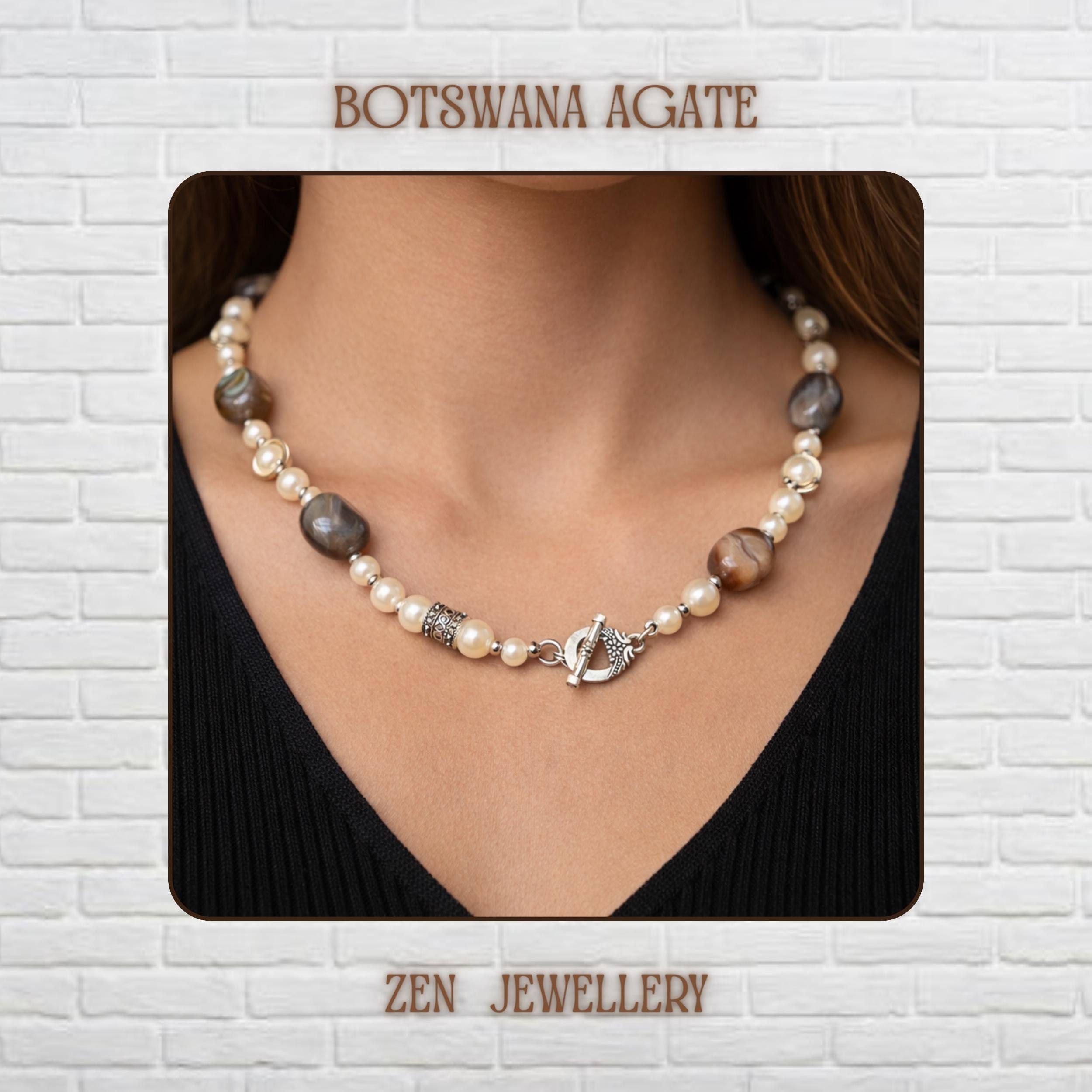 Elegant BOTSWANA AGATE gemstone necklace displayed on a textured dark background featuring polished grey striped agate stones combined with creamy ivory pearl beads and decorative silver rhinestone spacers. The handmade layered design creates a sophisticated bohemian appearance with soft neutral tones and artistic balance. Large oval agate stones become focal points throughout the necklace while silver chain details and toggle closure add vintage