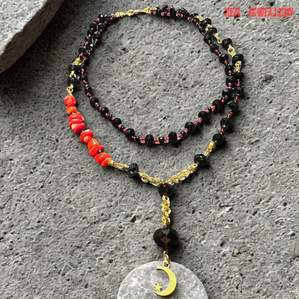 Detailed image highlighting the large geometric black stone pendant suspended beneath faceted black crystal beads and vibrant coral details. The luminous white pearl-like shell inlay creates elegant contrast against the deep black tones while the layered strands provide sophisticated statement style. The necklace combines organic gemstone textures with modern artistic fashion.