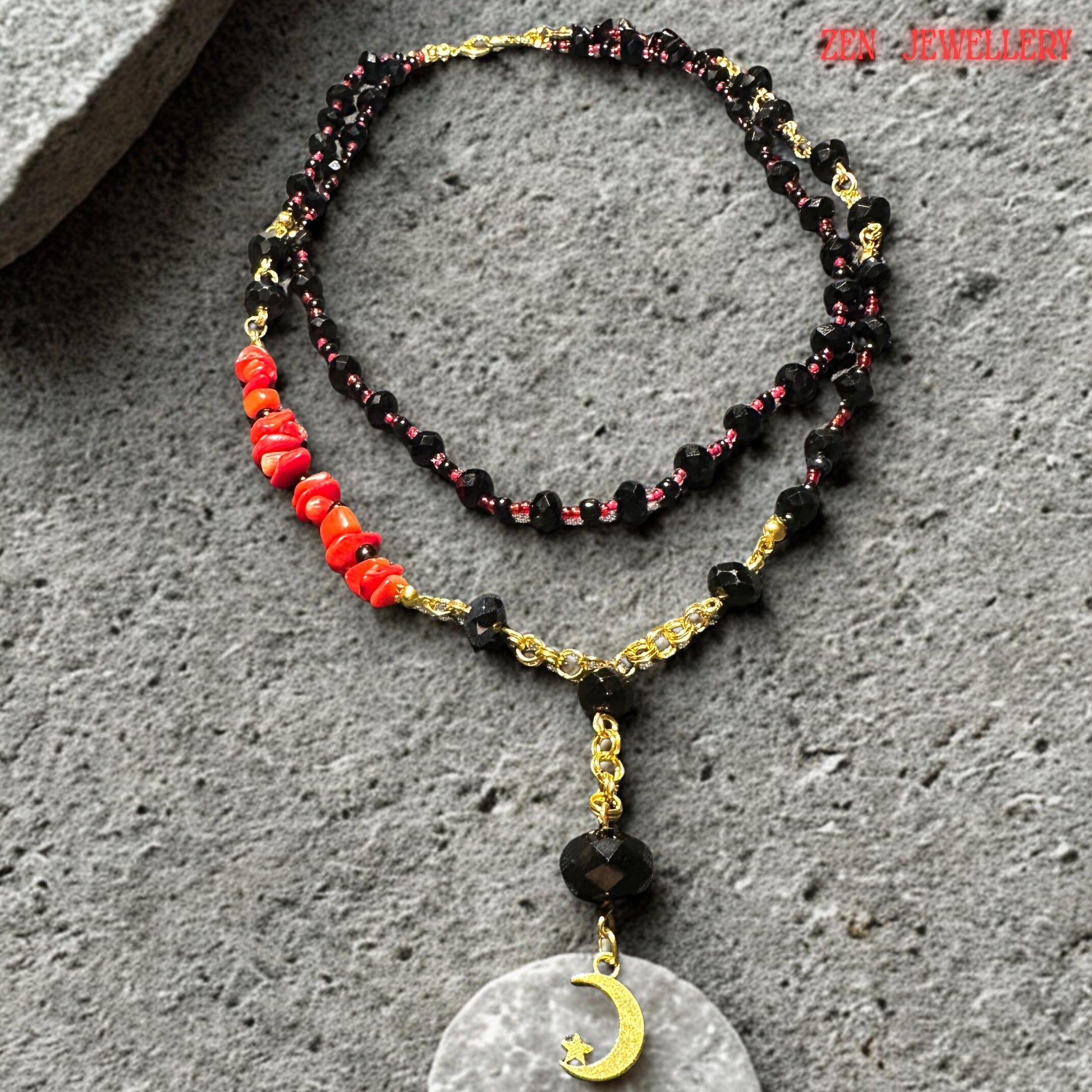 Side-angle photograph of the handmade black crystal necklace, showing the flowing, layered strands and faceted gemstone texture. Red coral chips are positioned asymmetrically for artistic balance, while gold connectors add warmth and elegance to the dark crystal design. The necklace makes a bold statement while remaining lightweight and comfortable.