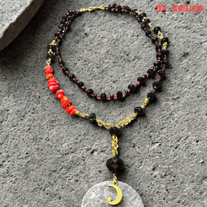 Side-angle photograph of the handmade black crystal necklace, showing the flowing, layered strands and faceted gemstone texture. Red coral chips are positioned asymmetrically for artistic balance, while gold connectors add warmth and elegance to the dark crystal design. The necklace makes a bold statement while remaining lightweight and comfortable.