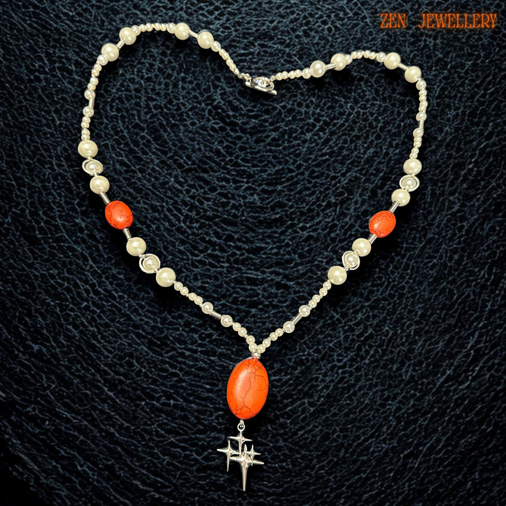 Elegant coral and pearl statement necklace photographed on a model showing the graceful Y-shaped drop design that elongates the neckline beautifully. The creamy white pearl-style beads add vintage elegance while the vivid coral-red gemstones create warmth and visual impact suitable for romantic boho styling and special occasion wear.