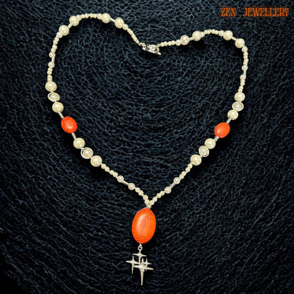 Elegant coral and pearl statement necklace photographed on a model showing the graceful Y-shaped drop design that elongates the neckline beautifully. The creamy white pearl-style beads add vintage elegance while the vivid coral-red gemstones create warmth and visual impact suitable for romantic boho styling and special occasion wear.
