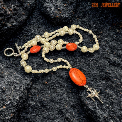 Close-up of red coral gemstone and pearl bead arrangement.