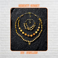 Handmade jade gemstone necklace and bracelet set featuring warm yellow jade, honey jade, amber beads, and champagne crystal beads with gold spacer details and a delicate gold clasp. The layered design sits on a dark textured stone background and creates a rich earthy luxury look with graceful movement.