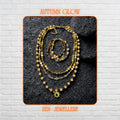 A layered boho necklace and bracelet set featuring warm earth-tone crystals and a gold sun charm on a textured stone background.