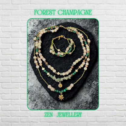 • Elegant handmade layered AVENTURINE jewellery set displayed on a dark volcanic stone background, featuring three delicate necklace strands and a matching double strand bracelet in soft green, ivory, cream, and earthy tones. The design combines polished aventurine gemstones, creamy jade style beads, green striped malachite style beads, metallic seed beads, rhinestone spacer rings, and warm gold accents that reflect light beautifully for a luxuri