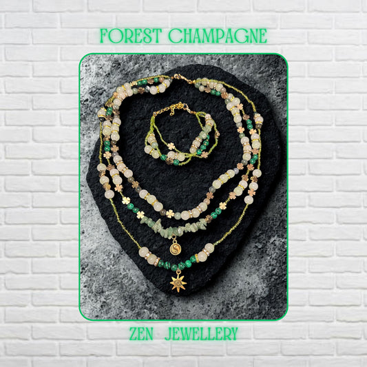 • Elegant handmade layered AVENTURINE jewellery set displayed on a dark volcanic stone background, featuring three delicate necklace strands and a matching double strand bracelet in soft green, ivory, cream, and earthy tones. The design combines polished aventurine gemstones, creamy jade style beads, green striped malachite style beads, metallic seed beads, rhinestone spacer rings, and warm gold accents that reflect light beautifully for a luxuri