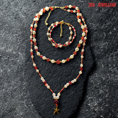 Matching handmade bracelet displayed above the necklace featuring alternating ruby red crystal beads and pearl white gemstone beads finished with a delicate gold adjustment chain and tiny star charm. The bracelet mirrors the layered necklace design beautifully creating a coordinated jewellery set full of sparkle texture and warm luxurious bohemian elegance perfect for gifting or occasion styling.