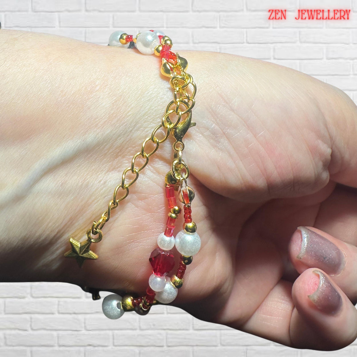 Luxury red crystal jewellery set with white pearls and gold accents top view on a model wrist.