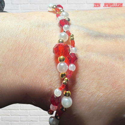 Elegant red and pearl layered bracelet styled on the model's wrist. Red ruby crystals and pearls with delicate golden beads.