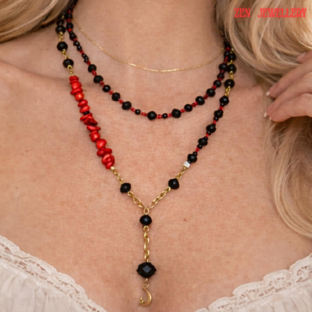 Detailed image highlighting the gold moon pendant suspended from a faceted black crystal bead at the centre of the layered necklace. The surrounding glossy black crystal beads and small red gemstone details create a luxurious monochrome look with subtle bold colour accents. The necklace combines celestial symbolism with modern geometric jewellery design.