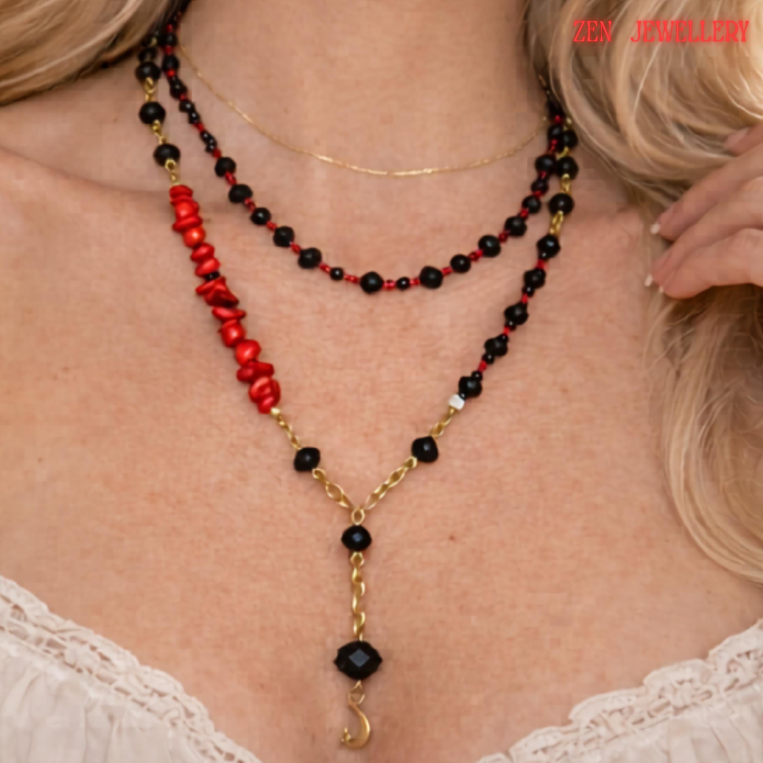 Detailed image highlighting the gold moon pendant suspended from a faceted black crystal bead at the centre of the layered necklace. The surrounding glossy black crystal beads and small red gemstone details create a luxurious monochrome look with subtle bold colour accents. The necklace combines celestial symbolism with modern geometric jewellery design.