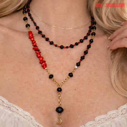 Detailed image highlighting the gold moon pendant suspended from a faceted black crystal bead at the centre of the layered necklace. The surrounding glossy black crystal beads and small red gemstone details create a luxurious monochrome look with subtle bold colour accents. The necklace combines celestial symbolism with modern geometric jewellery design.