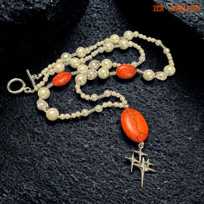 Detailed product image of handmade pearl and coral necklace highlighting the natural crackle texture of the large oval red gemstone pendant and the polished silver star charm suspended below. Smaller matching coral-effect beads are positioned symmetrically on each side creating balance and refined artisan craftsmanship throughout the jewellery design.