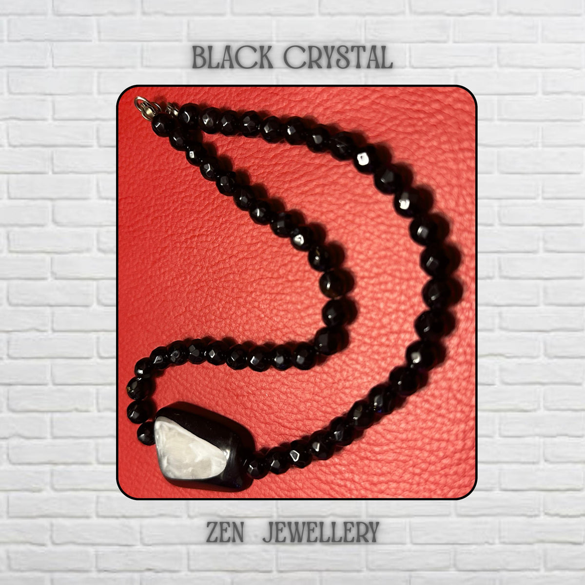 Close-up image of a black crystal necklace bracelet set handcrafted with glossy faceted black beads and a bold geometric pendant featuring a natural shell or pearl-style white centre. The polished black crystal beads reflect surrounding light beautifully, adding sparkle and texture across the necklace strand. The jewellery rests against a rich red textured background that enhances the dramatic black monochrome tones and luxurious handcrafted appe