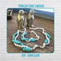 Turquoise pearl necklace displayed on a wood platform, showing 2 strand design with white pearls and turquoise chips, a sterling silver chain visible, styled as layered boho jewellery with a matching bracelet below, highlighting elegant contrast and natural textures.
